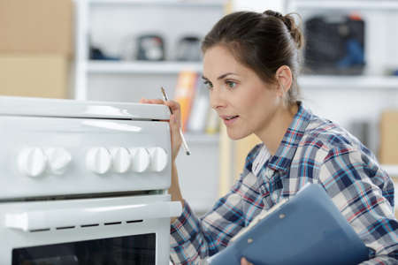 woman with clipboard inspecting ovenの写真素材