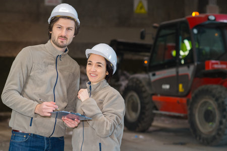two workers with clipboard in dark warehouse