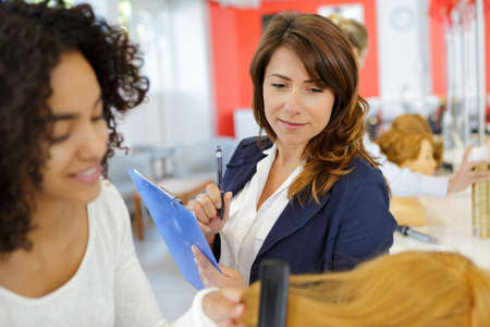 female hairdressing apprentice combing hairの写真素材