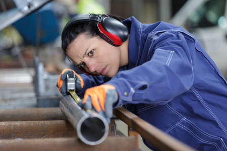 the worker measures and marks something on the pipes