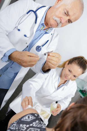 senior doctor injecting patient with syringe to collect bloodの写真素材