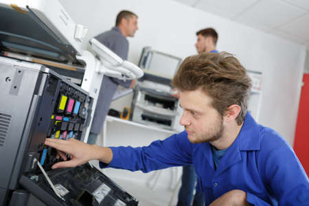 young male technician working on photocopierの写真素材