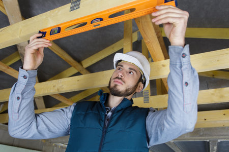 construction site worker with spirit level checking beam