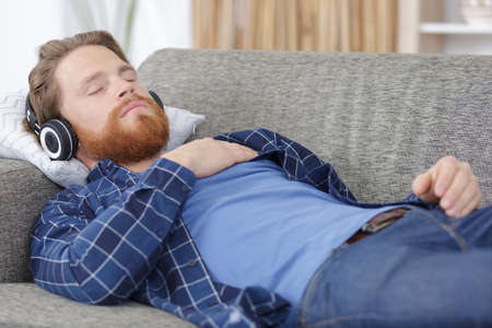 young man in sofa with headphonesの写真素材