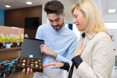 happy blonde pensioner buying chocolate in candy shopの写真素材