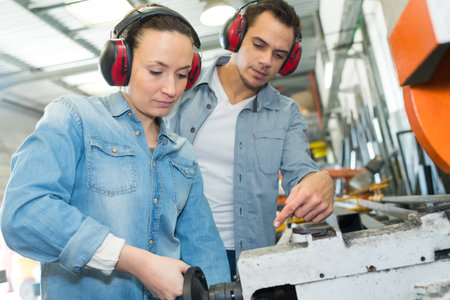 engineer and apprentice working on machine in factory