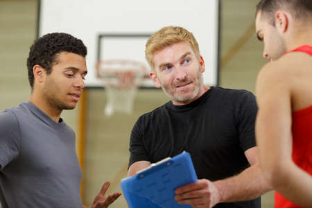 thoughtful basketball players with coach standing at courtの写真素材