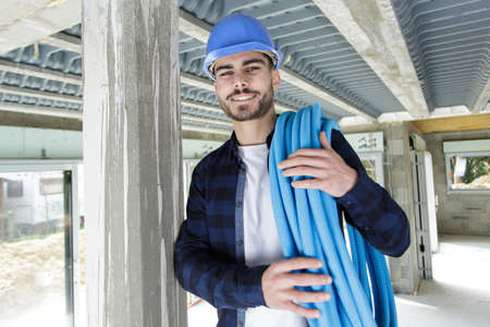 young technician holding water pipes indoors