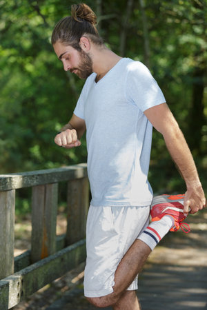 young fitness man runner stretching legs before running