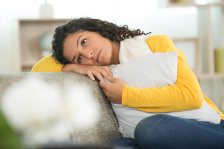portrait of sad young woman sitting by sofa at home