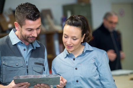 two stonemasons looking at stone in workshopの写真素材