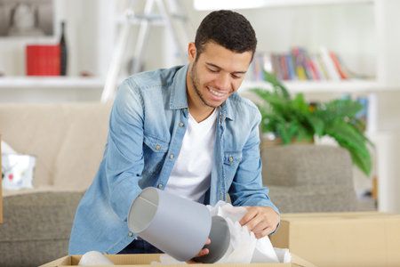 young man in the home unpacking lamp from carboard box