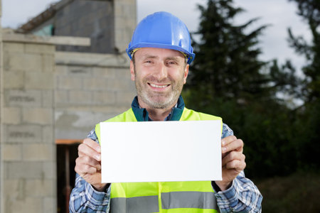 happy male engineer holding an advertisement blank banner