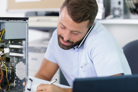 computer engineer on the phone repairing broken desktop