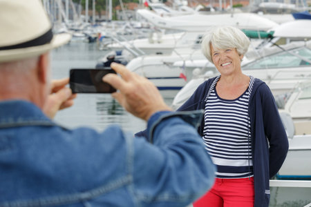 senior man photographing his wife in a marina