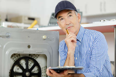 manual worker thinking about how to fix a machineの写真素材