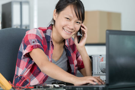 happy female technician on the phone repairing a computer