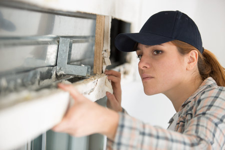 female builder working on crumbling window frame