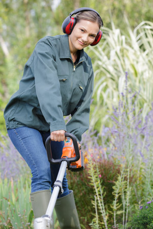 woman with lawn mower on green grass