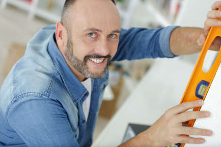 man using a spirit level to check a surfaceの写真素材