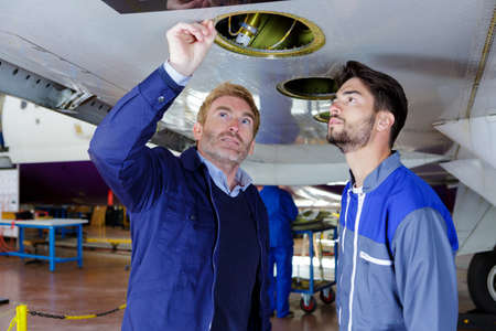 two modern aircraft engineers in hangarの写真素材