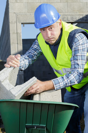 bricklayer putting bricks on wheelbarrow