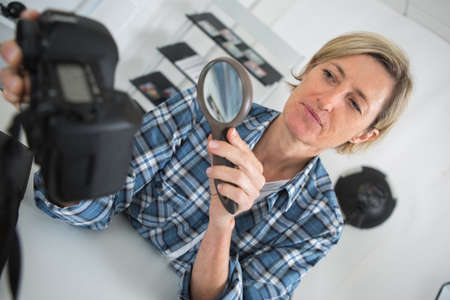 woman photographer checking her lens with magnifying glassの写真素材