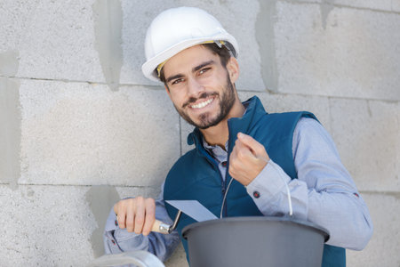happy young man plastering a brick wall