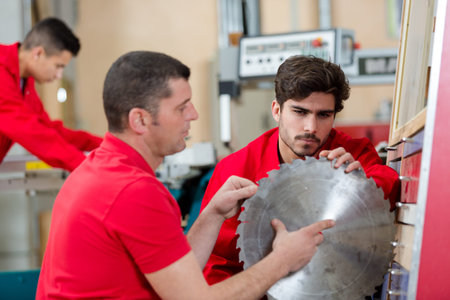 workers inspecting teeth on circular blade for saw