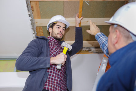 junior building holding hammer receiving instructions from foreman