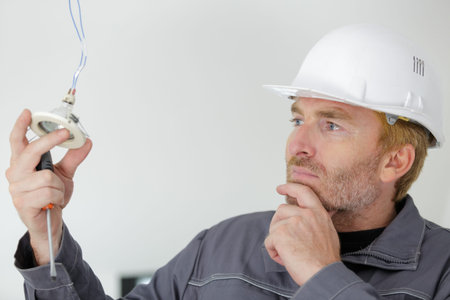 electrician man working with wires mounting lights in houseの写真素材