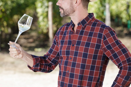 winegrower tasting wine in vineyard