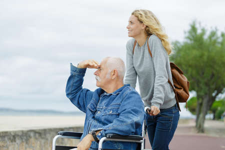 young woman with elderly man on a wheelchair outdoorsの写真素材