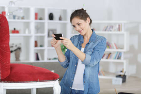 woman photographing a chair she has restoredの写真素材