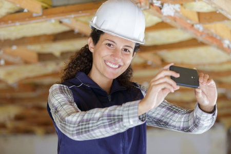 female builder taking photograph with smartphone