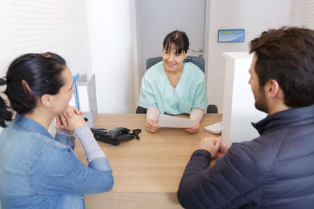 doctor woman having conversation with young couple in officeの写真素材