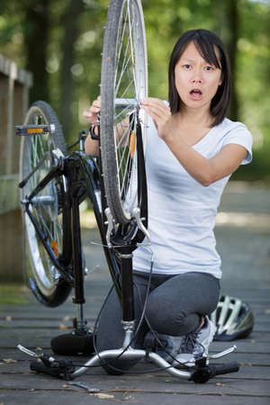 scared young woman can not fix her bikeの写真素材