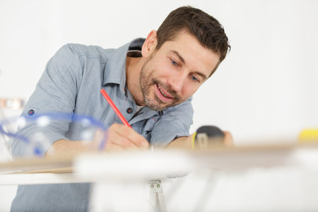 man marking a line with a pencil on a board