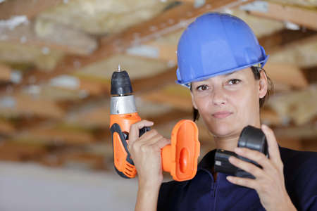 woman builder putting the driller batteryの写真素材