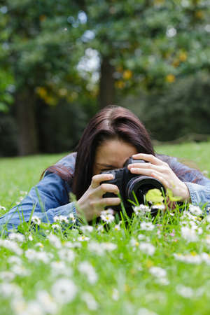 young woman using dslr outdoor laying on grassの写真素材