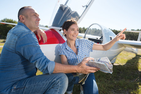 man and woman squatting next to a glider plane