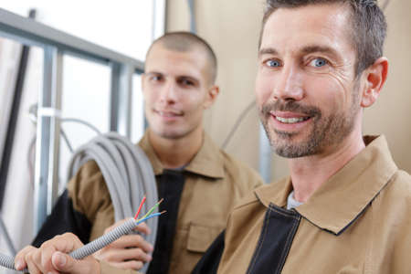 a happy electrician holding corrugated wireの写真素材