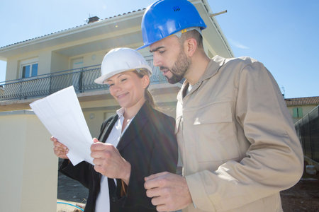 businesswoman and builder outside in front of building
