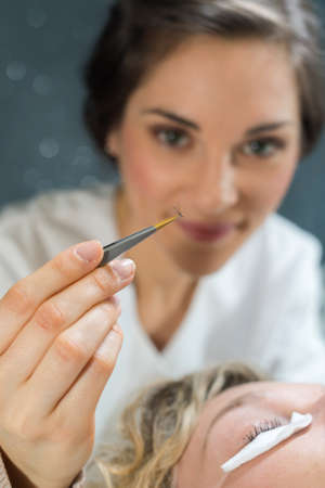 applying false eyelashes with tweezersの写真素材
