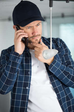 confused technician talking on the phoneの写真素材