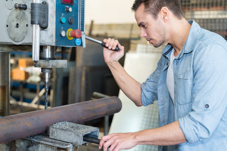 mature man using a drilling machine at industrial factoryの写真素材