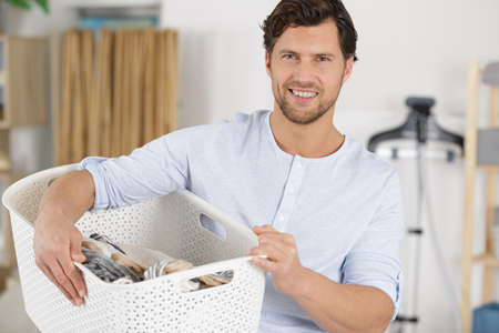 happy man is holding a laundry basketの写真素材