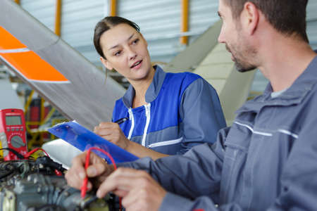 aero engineer and apprentice working in hangarの写真素材