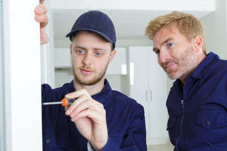 apprentice tradesman using scredriver supervisor watchingの写真素材