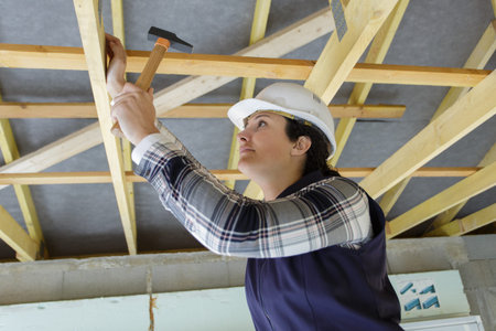 female carpenter hammering nail in wood at site